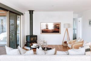 uma sala de estar com um sofá e um fogão a lenha em Omaru Beach House em Scamander