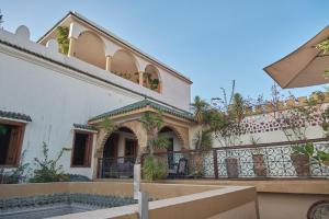 a house with a balcony and an umbrella at Riad Thamayna in Sale