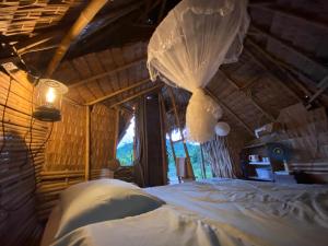 a bedroom with a bed with a mosquito net at Royal mountain Hut in Ratchaburi