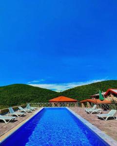 una piscina azul con sillas y sombrillas en Guest House Ilto en Akhmety