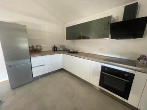 uma cozinha com armários brancos e um frigorífico de aço inoxidável em Apartman Ž em Ljubuski
