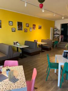a restaurant with tables and chairs and a yellow wall at Hannover Messe Apartment 2 in Hannover