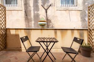 une table et deux chaises devant un mur dans l'établissement Casa De Rollo - Whole House, à Noto