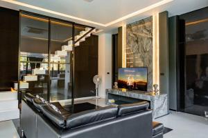 ein Wohnzimmer mit einem Ledersofa und einem Kamin in der Unterkunft Futuristic Pool Villa with Stunning Mountain View in Chiang Mai