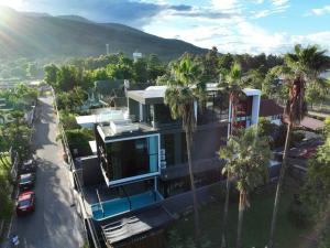 ein Haus mit Palmen vor einem Berg in der Unterkunft Futuristic Pool Villa with Stunning Mountain View in Chiang Mai