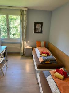 1 dormitorio con 2 camas, escritorio y ventana en Tulai D74 en Scuol