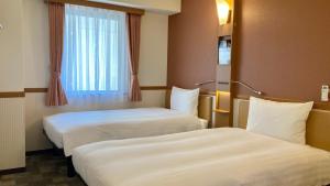 2 Betten in einem Hotelzimmer mit Fenster in der Unterkunft Toyoko Inn Hokkaido Hakodate Ekimae Asaichi in Hakodate