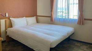 ein großes weißes Bett in einem Zimmer mit Fenster in der Unterkunft Toyoko Inn Hokkaido Hakodate Ekimae Asaichi in Hakodate