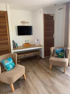 a living room with two chairs and a tv at B&B LES VOILES DE VALESCURE chambres d'hôtes et son espace bien être in Saint-Raphaël