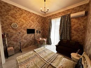 een slaapkamer met een bed, een bank en een televisie bij STEPROOMS in Tbilisi City