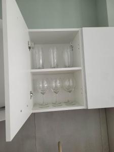 a cupboard with four wine glasses in it at Apartament Wałowa in Wejherowo