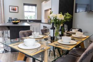 een eetkamer met een glazen tafel en stoelen bij Elizabeth Mews - By Luxury Apartments in Cheltenham