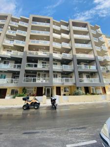 two motorcycles parked in front of a large apartment building at Mela Apartment 1 in St. Paul's Bay