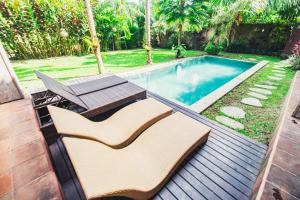 einen Pool mit Stühlen und einem Tisch neben einem Hof in der Unterkunft Warisan Villa by Supala in Ubud
