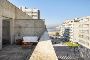 a balcony with a couch and a view of a city at Ocean Front 4-bed Luxury w/ Terrace & Parking in Matosinhos