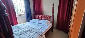 a bed in a bedroom with red curtains at cosy living in Gulu
