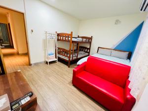 Xingang Ping An B&B في Xingang: غرفة معيشة مع أريكة حمراء وسرير