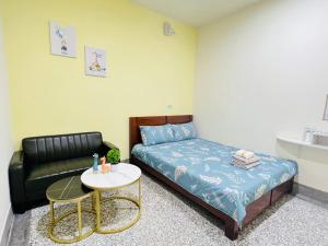 1 dormitorio con cama, sofá y mesa en Xingang Ping An B&B en Xingang