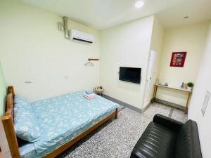 1 dormitorio con cama, sofá y TV en Xingang Ping An B&B en Xingang