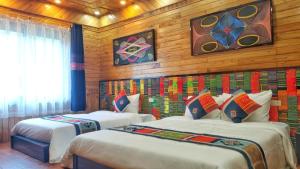 two beds in a room with wooden walls at Rose House Sapa in Sa Pa