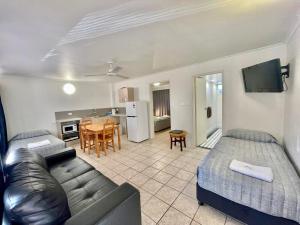 a living room with a bed and a couch and a kitchen at Yongala Lodge by The Strand in Townsville