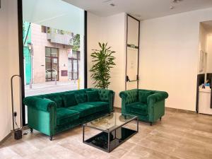 a living room with two green couches and a table at Hotel MG Poniente in Las Palmas de Gran Canaria