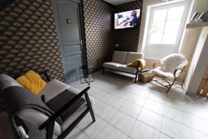 a living room with a couch and chairs and a tv at Domaine des demoiselles - Chambres d'hôtes in Hauteville