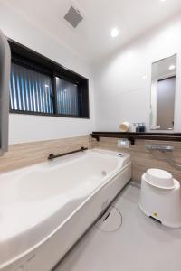 Baño blanco con bañera y lavamanos en ‐izen 高田‐ 楽酔亭, en Joetsu