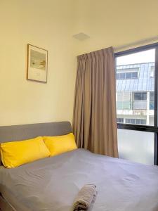 a bedroom with a bed with yellow pillows and a window at 2 BR with city view near Subway in central in Singapore