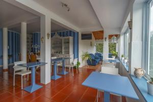 Habitación con mesas y sillas azules y ventanas. en Quinta das Hortências, en São Vicente Ferreira