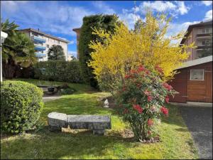 a garden with a stone bench and a bush with flowers at Individual house free parking wifi Netflix Disney next to EPFL Lausanne in Ecublens