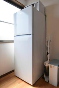 a white refrigerator in a room with a toilet at メゾン八千代302 in Tokyo