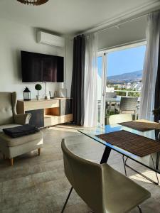 Malibu Park Apartments Sol في أديخي: غرفة معيشة مع طاولة وكراسي وتلفزيون