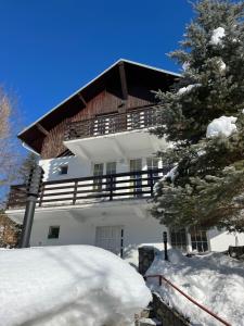 a white house with a wooden roof in the snow at Casa Floarea de Colt in Azuga