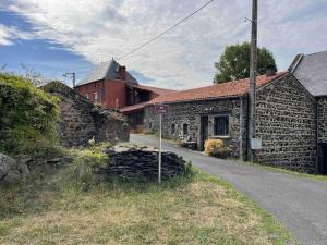 una antigua casa de piedra con un edificio rojo en el fondo en La clé des champs de Laumont en Saint-Diéry