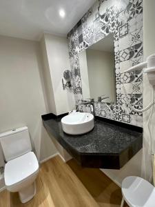 ein Badezimmer mit einem Waschbecken, einem WC und einem Spiegel in der Unterkunft Apartamentos Turisticos Poblado in Arinsal