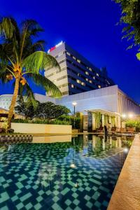 a hotel with a swimming pool in front of a building at d'primahotel Tangerang in Tangerang