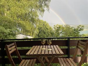 uma mesa de madeira com 2 copos de vinho na varanda em Haus Magnolia em Techelsberg am Worthersee