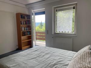 een slaapkamer met een bed, een boekenplank en een raam bij Haus Magnolia in Techelsberg am Worthersee