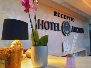 a vase with flowers in it on a table at Hotel Ancora in Eforie Sud