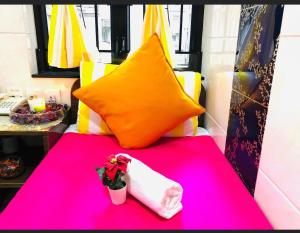 Ashoka Hostel في هونغ كونغ: طاولة وردية عليها وسادة و إناء من الزهور