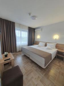 a large bedroom with a large bed and a chair at Hotel Ancora in Eforie Sud