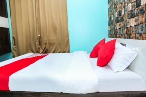a bed with red and white pillows on it at OYO Hotel Sonar Gaon in Agartala