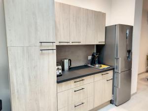 eine Küche mit Holzschränken und einem Edelstahlkühlschrank in der Unterkunft Maison proche centre ville clim jardin wifi 8 personnes in Amiens + 22 Fotos