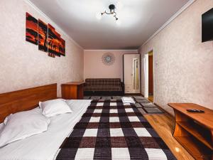 1 dormitorio con 1 cama y suelo a cuadros en Тасс уютная квартира в центре города, en Petropavlovsk