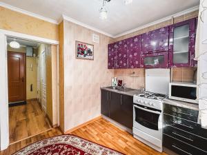 cocina con armarios morados y horno con fogones en Тасс уютная квартира в центре города, en Petropavlovsk