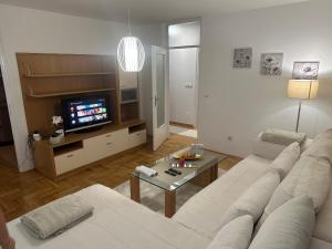 a living room with a white couch and a television at Perla stan Breka in Sarajevo
