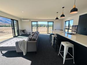 a living room with a couch and a kitchen with windows at Manuka Vista in Twizel