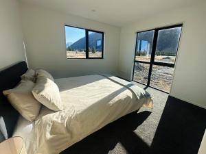 sypialnia z łóżkiem i dwoma dużymi oknami w obiekcie Manuka Vista w mieście Twizel