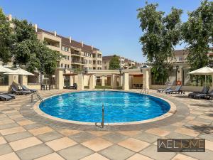 a pool in a courtyard with chairs and a building at WelHome - Prime Apartment With Balcony Amidst Lively Area in Dubai